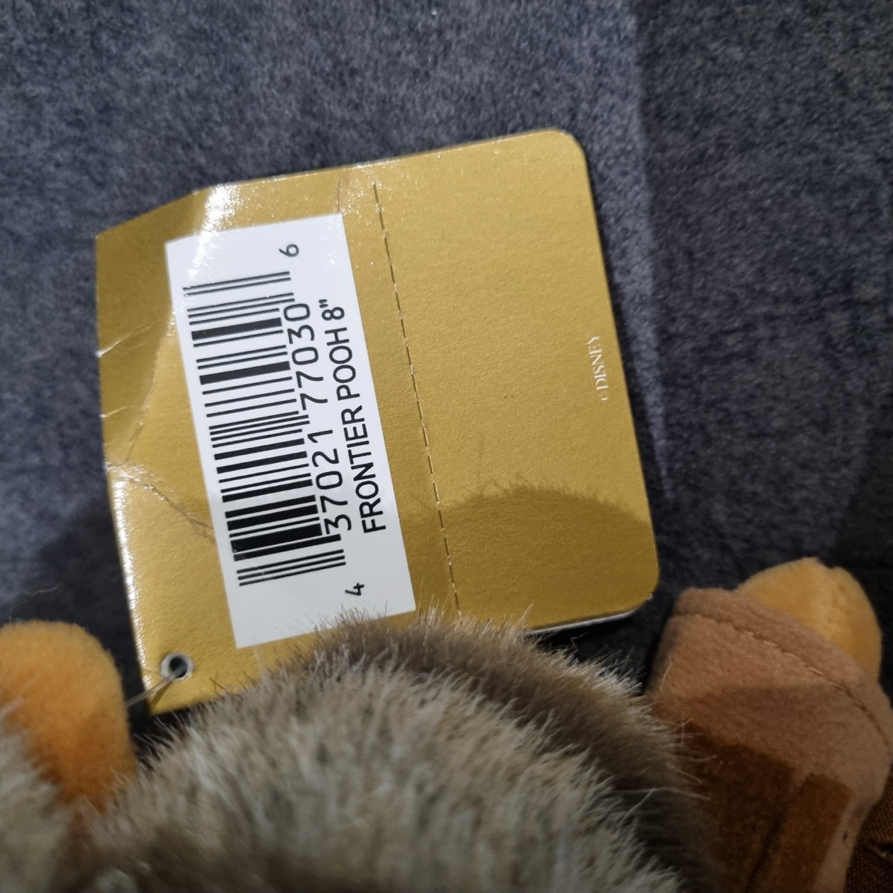 Close-up of the Disney Store gift tag reading Frontier Pooh 8 inch with barcode