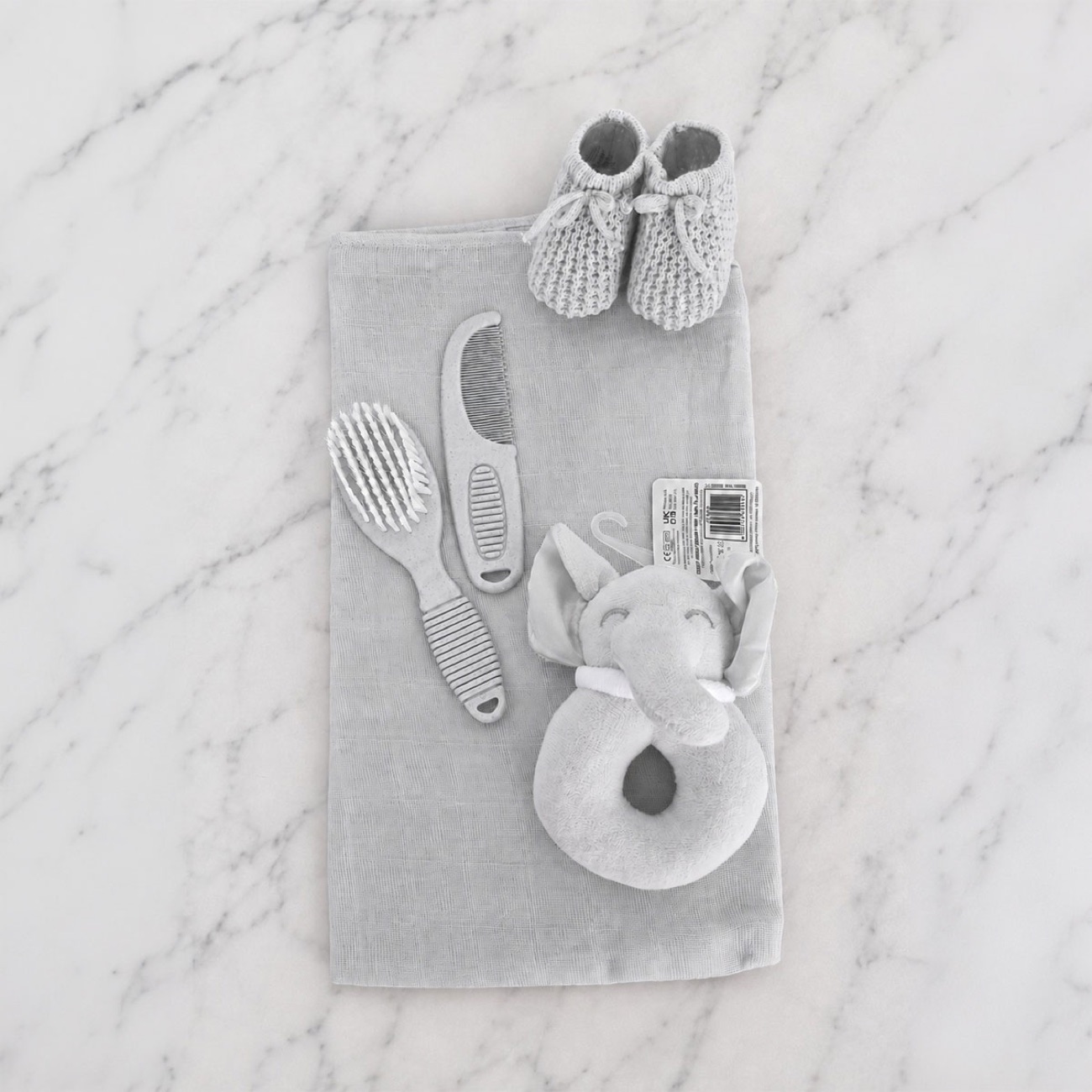 Contents of the grey nappy cake — grey muslin square, knitted booties, brush & comb set and elephant rattle