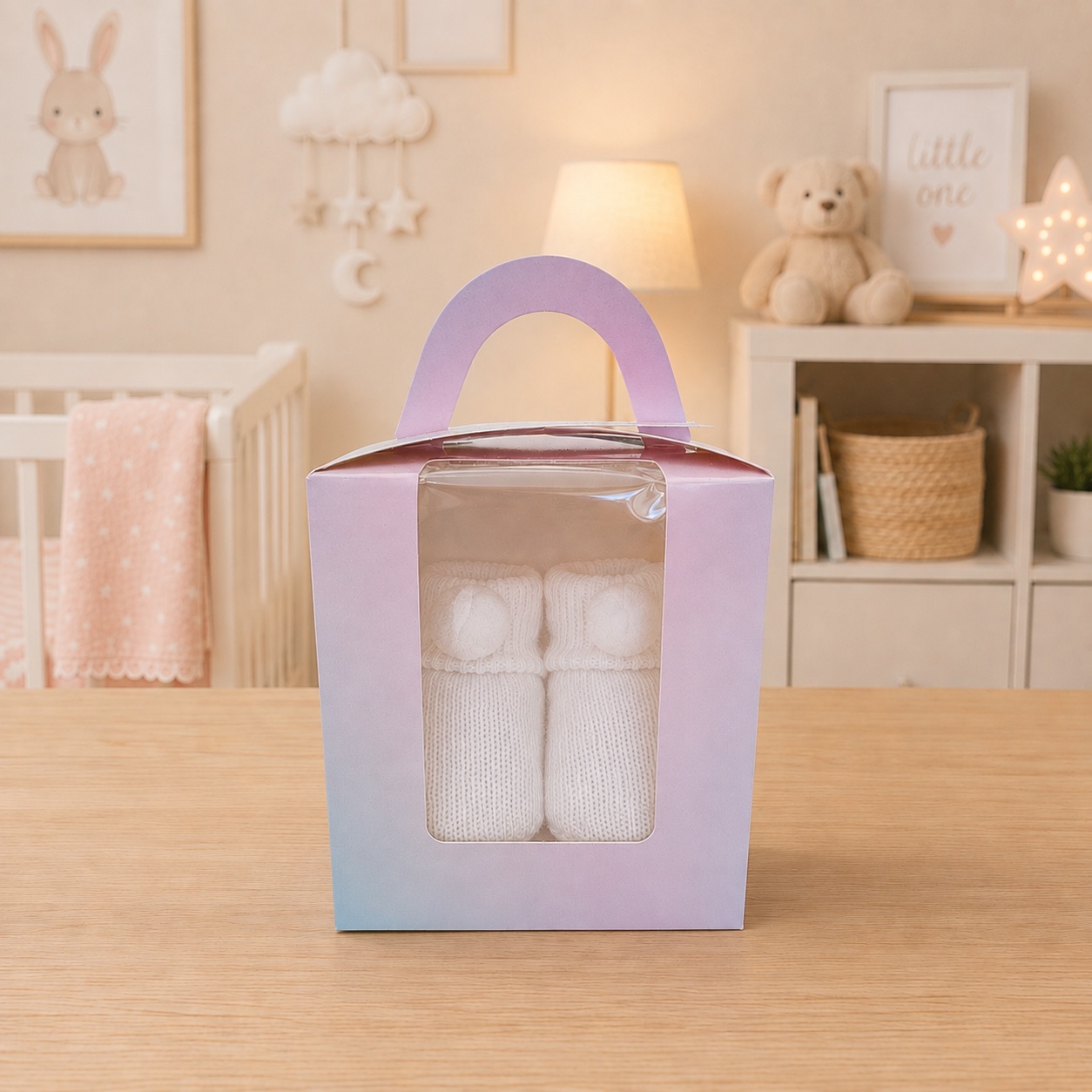 White pom-pom knitted baby booties presented in a pastel gift box