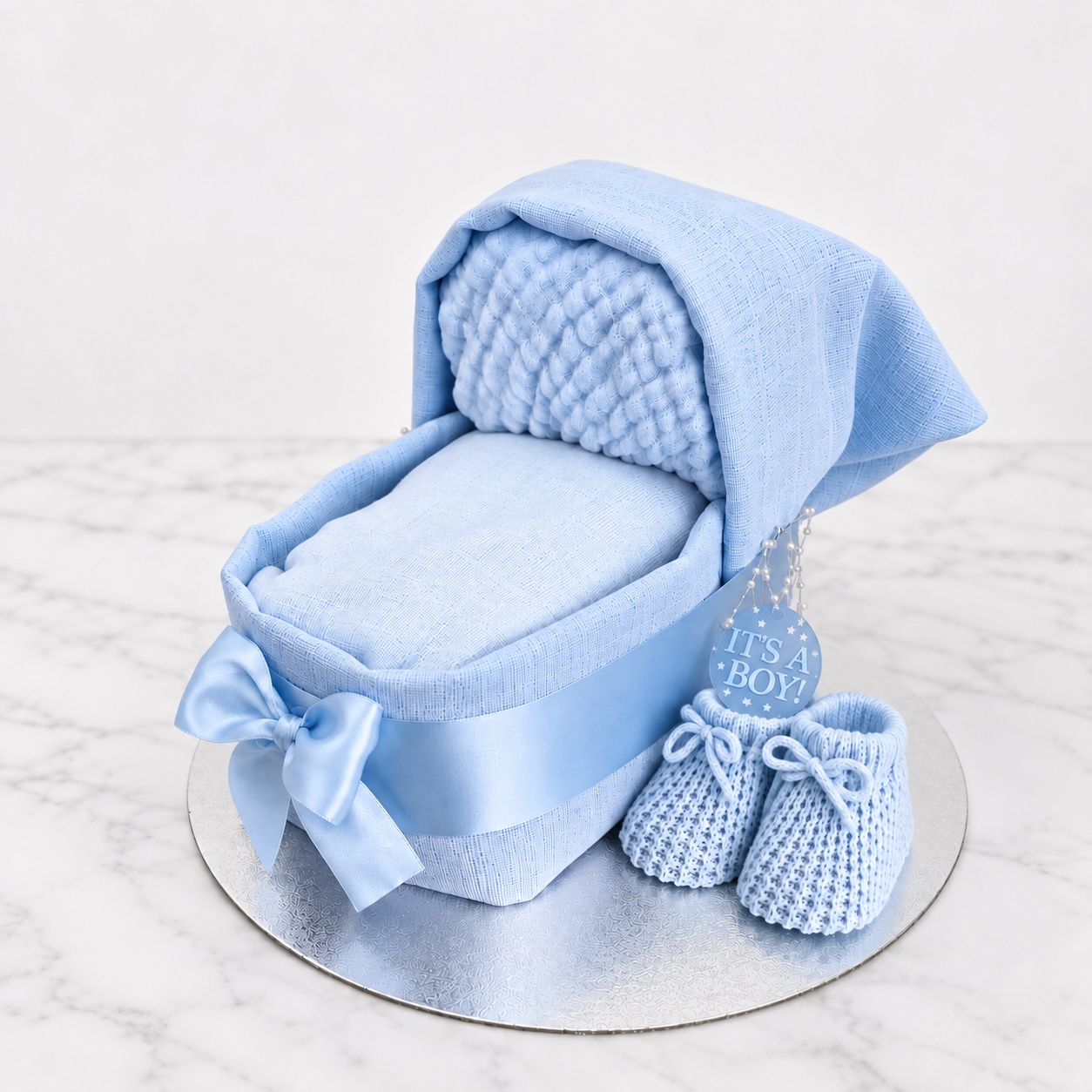 Small blue nappy cake pram with booties for a baby boy