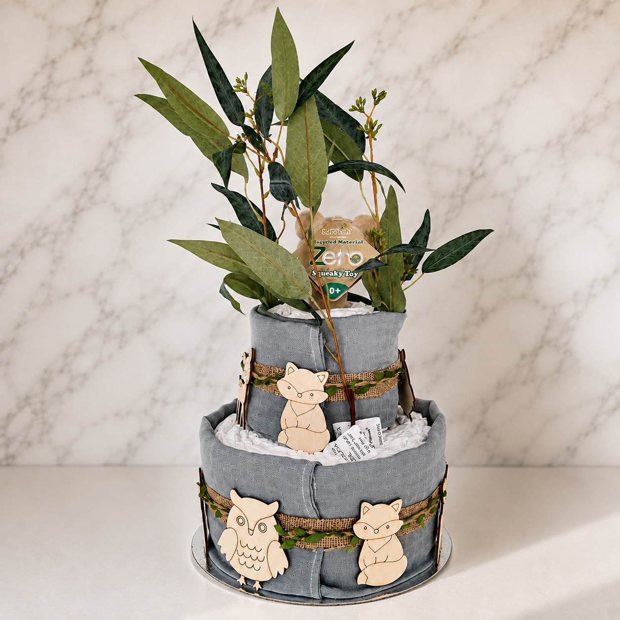 Woodland nappy cake with wooden owl and fox animals, burlap ribbon and eucalyptus foliage
