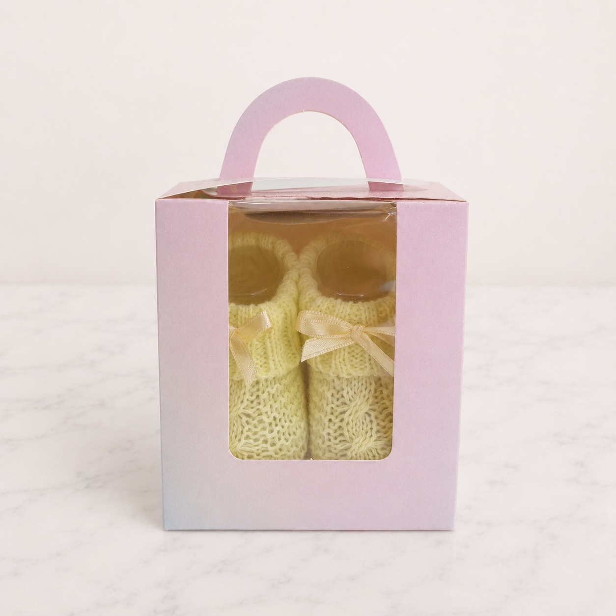 Pastel yellow knitted baby booties with cream bows